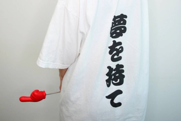 「夢を持て」という文字が印刷されている白いTシャツを着ている丸谷さんの写真